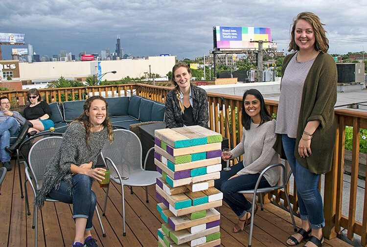 Photo of group by giant Jenga on the rooftop. 