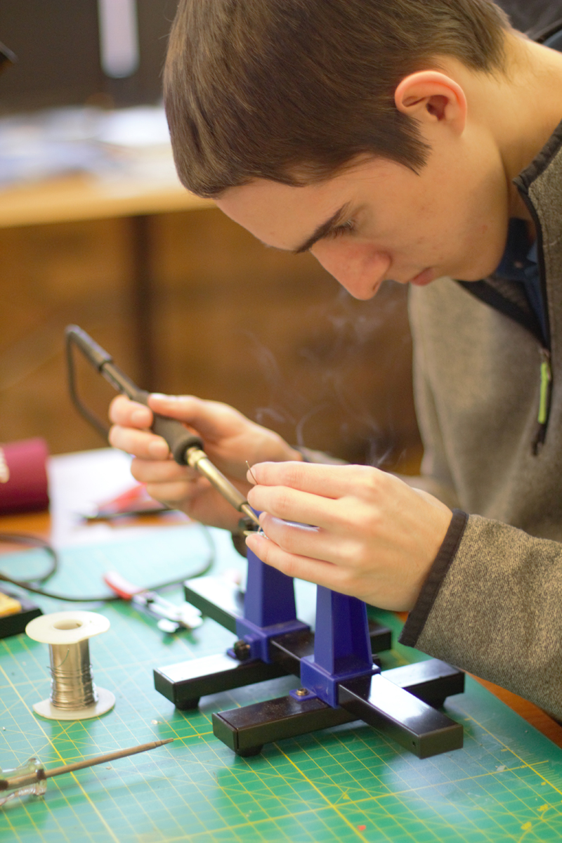 Photo of Caleb using the soldering tool.