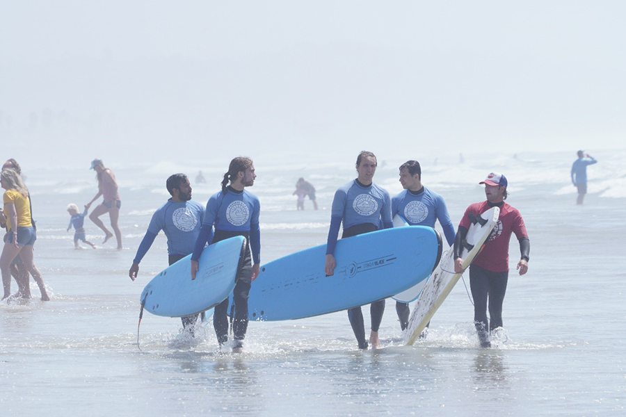 A group of surfers walk across the water