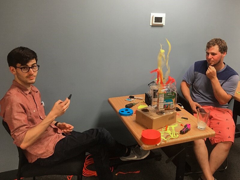 Photo of faux fire made of clear plastic container, fan, and red and yellow streamers.