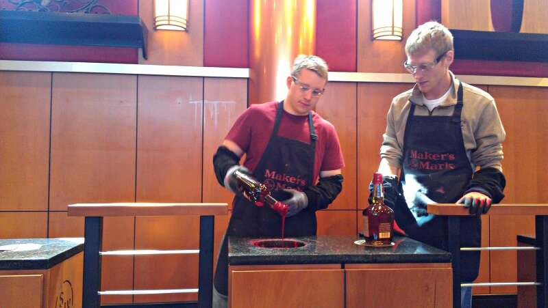 DMC Engineer dips a bottle of bourbon in wax.