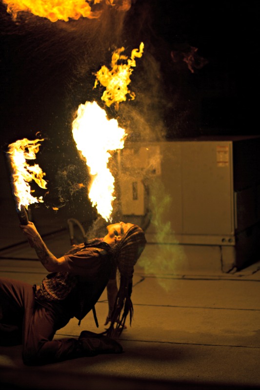 A fire breather draws a crowd on the rooftop.