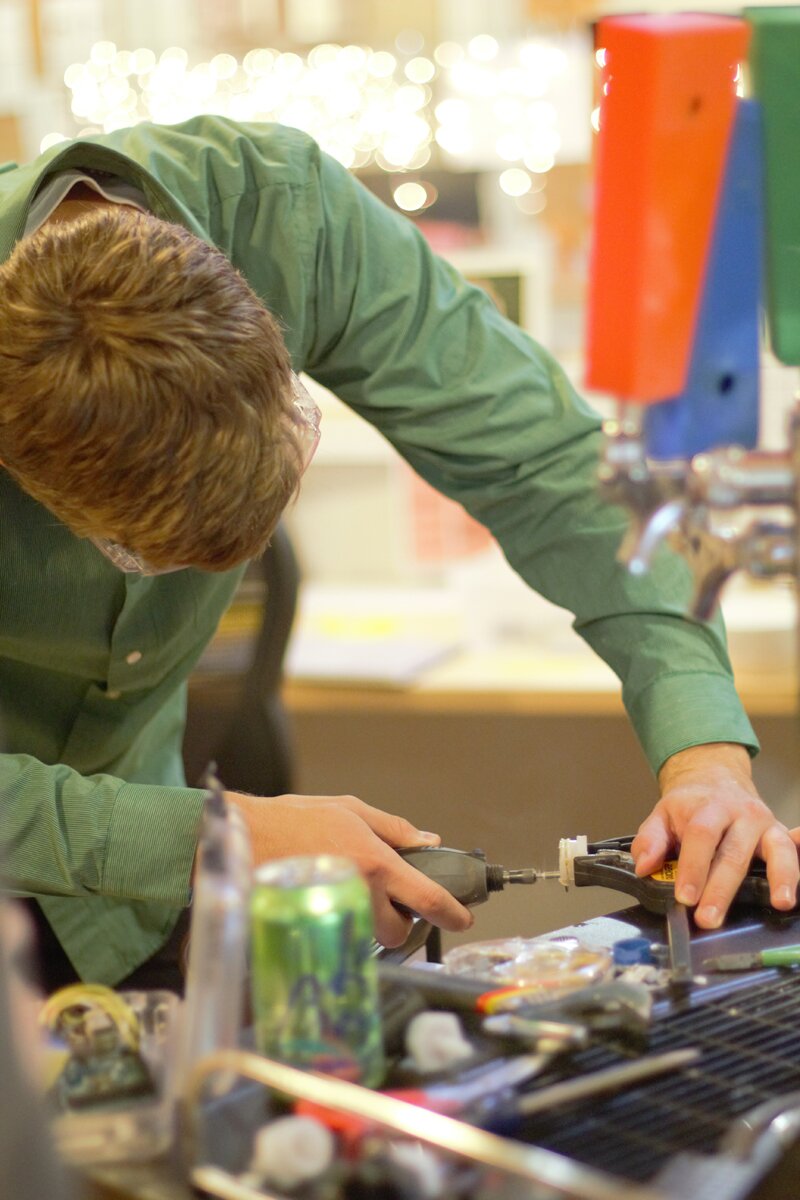 Photo of Nicklas shaving down parts for the IoT Kegerator.