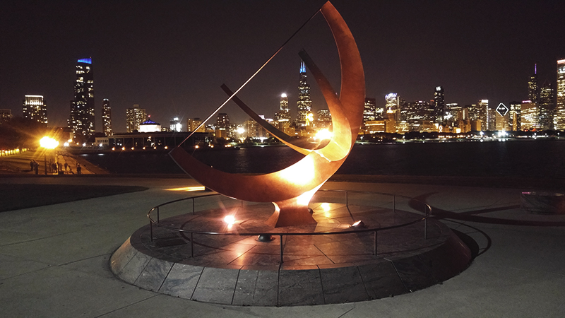 A statue outside the Adler Planetarium against the Chicago city skyline.