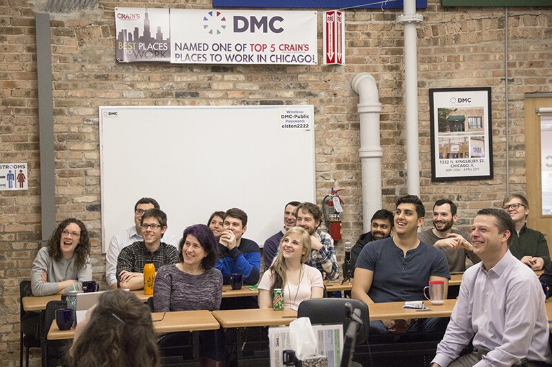 A photograph taken of DMC employees laughing at a DMC Monthly Company Meeting