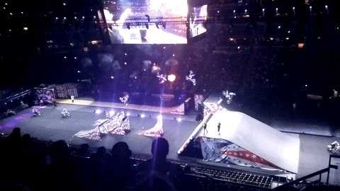 An animated GIF photo of dirt bikers doing flips off of ramps in a row during the opening stunts of Nitro Circus.