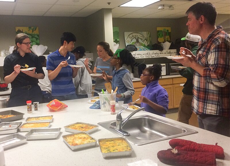 Photo of DMC trying food they made with the kids from Healthy Start.