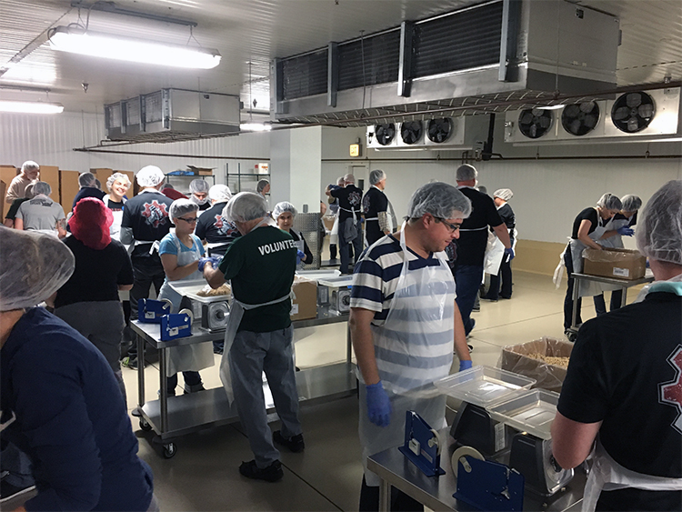 Photo of volunteers packing pasta in 3 pound bags.