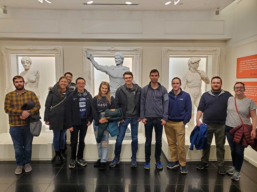 A group of people pose in front of Lego statues.