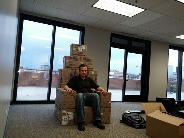 DMC engineer, Boris, sets atop a pile of boxes in the new Denver office.