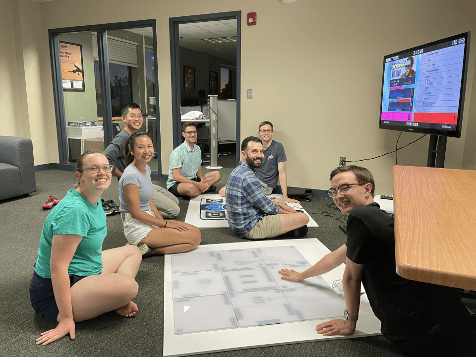 A group of people surrounding a DDR game