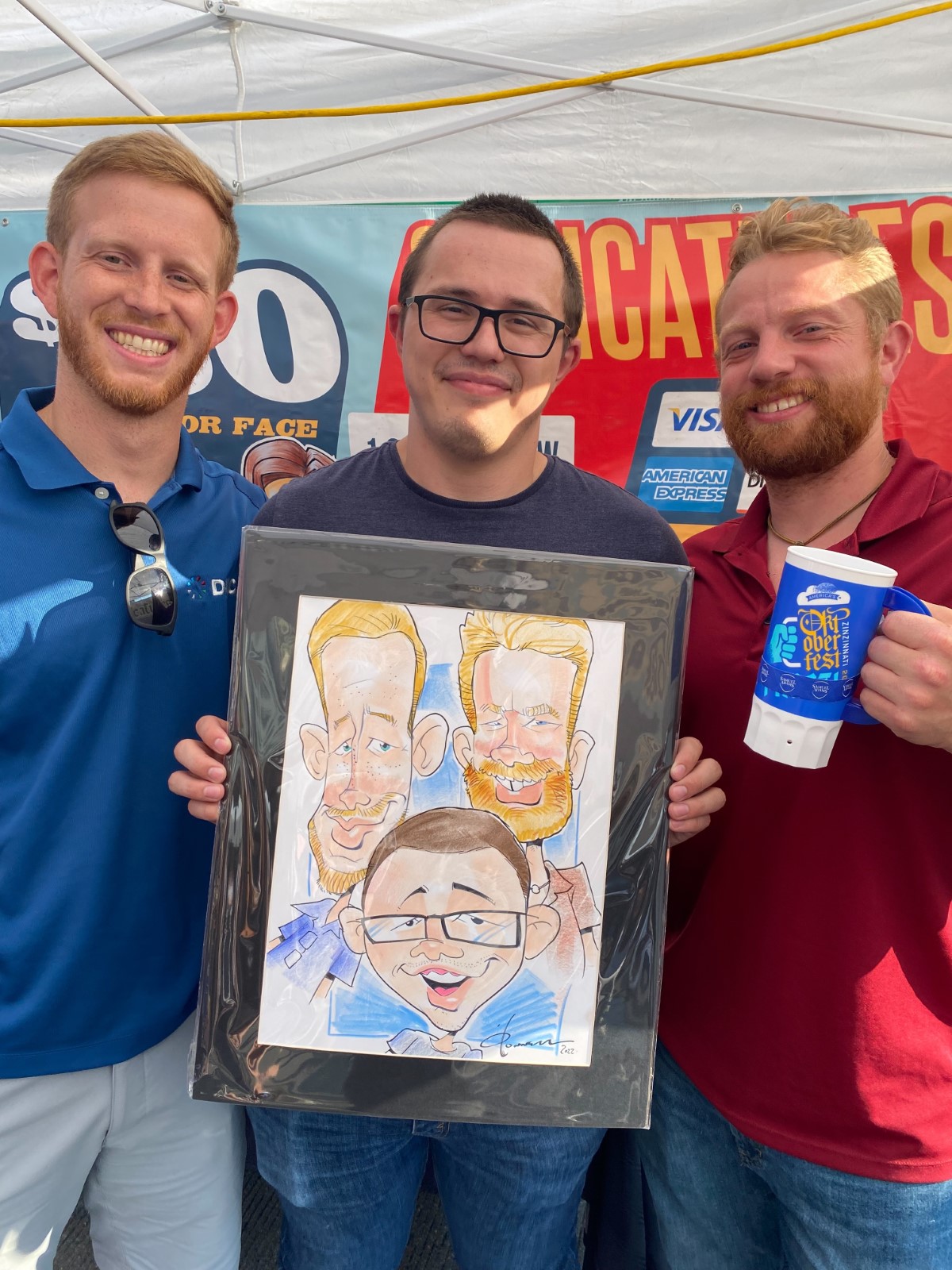 Three men hold a caricature of themselves at a fair.