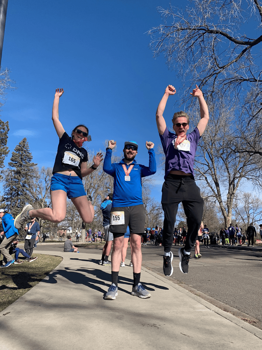 Three people in running attire pose at the finish line of a race