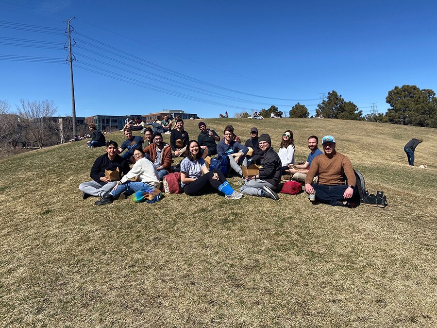 A group of people seated on a grassy hill.