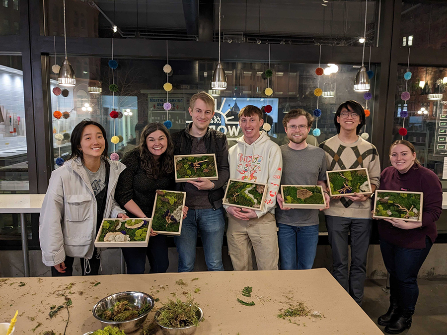 DMC's Seattle team poses with moss art in frames.