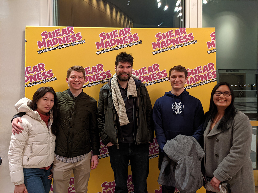 A group of people pose in front of a backdrop that reads "Shear Madness: Washington's Hilarious Whodunit!"